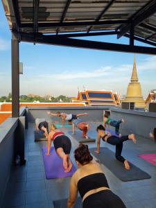 een groep mensen die yoga doen op een dak bij Issara by D Hostel in Bangkok
