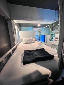 ein Schlafzimmer mit einem Bett mit einem schwarzen Hemd darauf in der Unterkunft Me U Hostel in Chiang Mai