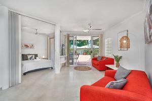salon z czerwoną kanapą i łóżkiem w obiekcie Golden Sands Beachfront Resort w mieście Yorkeys Knob