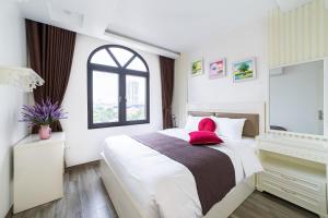 Rosee Apartment Hotel - Luxury Apartments in Cau Giay , Ha Noi في هانوي: غرفة نوم بسرير كبير ومخدة حمراء