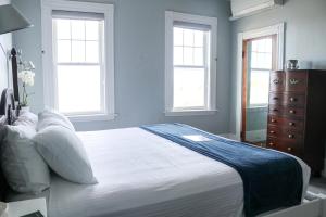 a bedroom with a large white bed with two windows at Emerson Inn By The Sea in Rockport