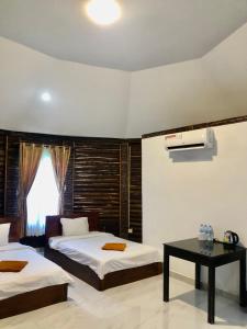 a bedroom with two beds and a table and a window at M'pay Bay Guesthouse in Koh Rong Sanloem