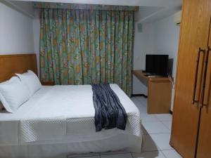 een slaapkamer met een bed, een gordijn en een televisie bij Flat 305 - Flat no Vip Praia Hotel in Natal