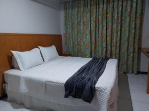 a bedroom with a white bed with a curtain and a window at Flat 305 - Flat no Vip Praia Hotel in Natal