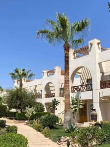 een groot wit gebouw met een palmboom ervoor bij Sunny lakes resort in Sharm El Sheikh
