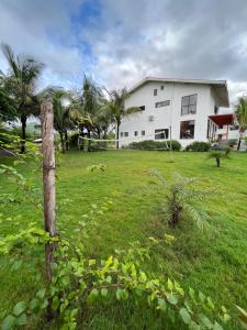 a white house with a field of grass and trees at The Green Estate Resort in Nashik