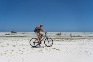 una mujer montando una bicicleta en la playa en Jambo Jambiani Beach Villa, Beautiful private villa at 2 minutes from the Beach en Jambiani