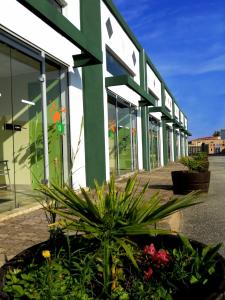 un bâtiment vert et blanc avec des plantes devant lui dans l'établissement Hôtel Restaurant Caribou, à Chassagny