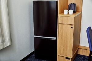 a black refrigerator sitting next to a wooden cabinet at Hotel Lumiere Kasai in Tokyo