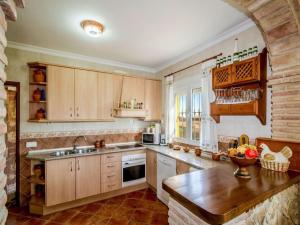 cocina grande con armarios de madera y fregadero en Appealing holiday home in Andaluc a with private pool, en La Joya