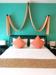 łóżko z pomarańczowymi i białymi poduszkami w pokoju w obiekcie Sudala Beach Resort w mieście Khao Lak