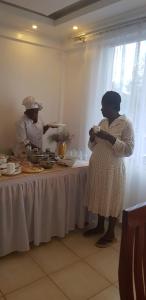 two women standing in front of a table with food at Hellenis Guest House in Kakamega