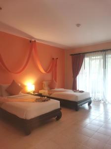 2 camas en una habitación con paredes de color naranja en Sudala Beach Resort, en Khao Lak