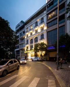 Rosee Apartment Hotel - Luxury Apartments in Cau Giay , Ha Noi في هانوي: مبنى فيه سيارات تقف امام شارع
