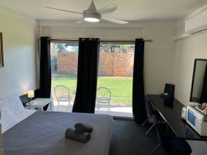 um quarto com uma cama, uma ventoinha de tecto e uma janela em Jumbuck Motor Inn - POOL - PET FRIENDLY SECTION - KING BEDS em Longreach