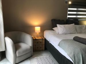 1 dormitorio con 1 cama, 1 silla y 1 lámpara en Aluve Guesthouse, en Johannesburgo