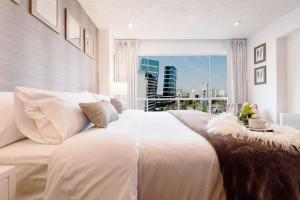 a bedroom with a large white bed with a large window at OceanFront Larcomar Apartments in Lima