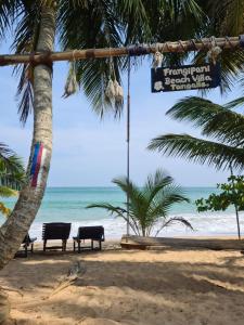 una playa con 2 sillas, palmeras y el océano en Frangipani Beach Villa, en Tangalle