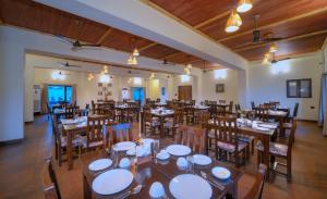 een eetkamer met houten tafels en stoelen bij Aranyak Resort Kanha in Dhanwār