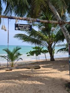 un columpio en una playa con el océano en el fondo en Frangipani Beach Villa, en Tangalle