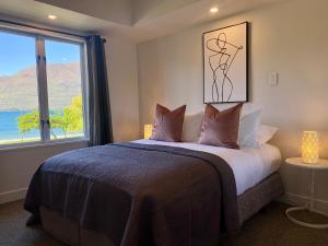 a bedroom with a bed and a large window at Lakefront Gem, Absolute Waterfront in Queenstown