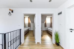 a hallway with white walls and wood floors and a staircase at Harmonija Lux in Vrdnik