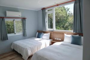 2 Betten in einem Zimmer mit 2 Fenstern in der Unterkunft 純粹Home 民宿 in Shui-wa-chüeh