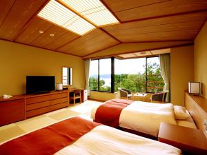 a bedroom with two beds and a large window at Jodogahama Park Hotel in Miyako