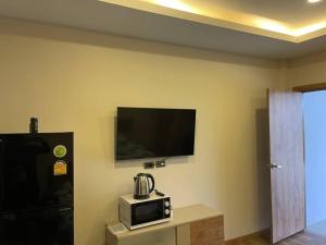 a living room with a microwave and a tv on the wall at SKY and STARLOFT in Ban Bang Phaniang
