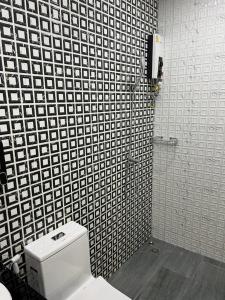 a bathroom with a toilet and a black and white tiled wall at SKY and STARLOFT in Ban Bang Phaniang