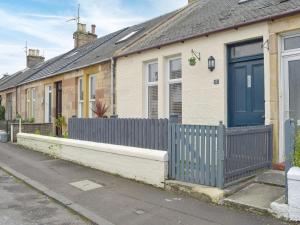 a house with a fence in front of it at Hunter Links Cottage in Prestwick