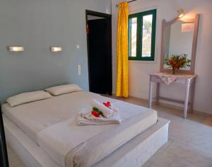 a bedroom with a white bed with towels on it at Apartments and Studios Xenophon in Matala