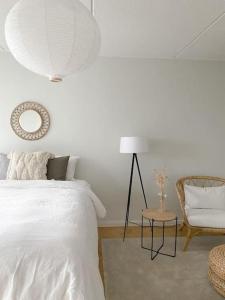 a white bedroom with a bed and a chair at Modern and cozy apartment with Sauna in Espoo
