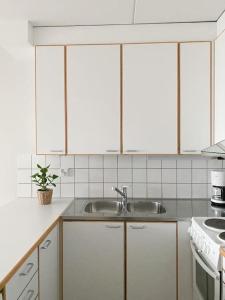 a kitchen with white cabinets and a sink at Modern and cozy apartment with Sauna in Espoo