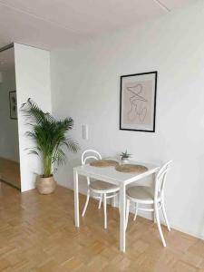 a white table and chairs in a room with a plant at Modern and cozy apartment with Sauna in Espoo