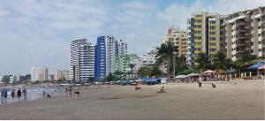 grupa ludzi na plaży z budynkami w obiekcie LA ESCONDIDA w mieście Tonsupa