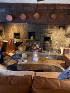 - un salon avec une cheminée en pierre, une table et des chaises dans l'établissement La Maison de Paul en Aubrac - Lozère, à Fontans