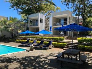 a house with blue umbrellas and chairs next to a pool at Valmarin Seafront Apartments in Trou dʼ Eau Douce