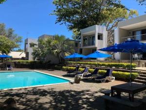 a villa with a swimming pool and blue umbrellas at Valmarin Seafront Apartments in Trou dʼ Eau Douce