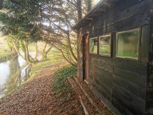 a building with windows next to a river at Fisherman's Cabin on the banks of the River Meon in Southampton +9 photos