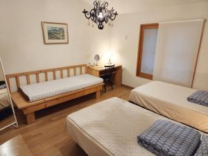 a bedroom with two beds and a desk and a chandelier at Tong Stay in Tongyeong