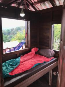 a bed in the inside of a cabin with a window at Mae Chan Treehouse with swimming pool in Mae Chan