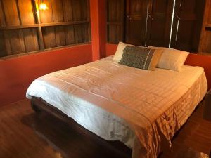 a bedroom with a white bed with an orange wall at Mae Chan Treehouse with swimming pool in Mae Chan