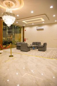 een wachtkamer met banken en een kroonluchter bij فندق روش بلس in Hafr Al Baten