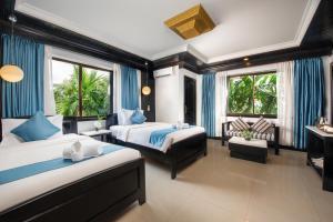 a hotel room with two beds and a couch at The Sanctuary Residence in Siem Reap