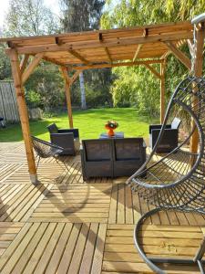 une terrasse en bois avec des chaises et une pergola en bois dans l'établissement Villa Cosy Pierrefonds, à Pierrefonds