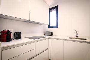 una cucina con armadi bianchi e lavandino di 3-1 Apartamento de diseño en el centro de Reus a Reus