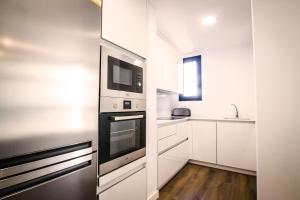 eine Küche mit weißen Schränken und einer Mikrowelle in der Unterkunft 3-1 Apartamento de diseño en el centro de Reus in Reus