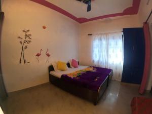 a bedroom with a bed with flamingos on the wall at Hobbit House Hostel in Rishīkesh