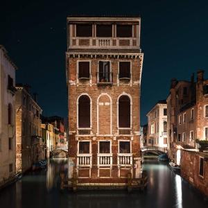 un gran edificio de ladrillo en un canal por la noche en Charme a Venise, en Venecia